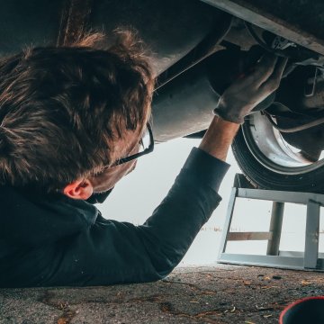 a mechanic fixing the underside of a car 